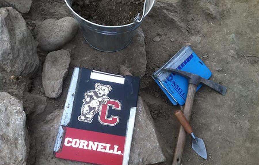 Cornell branded notebook with archaeological digging tools