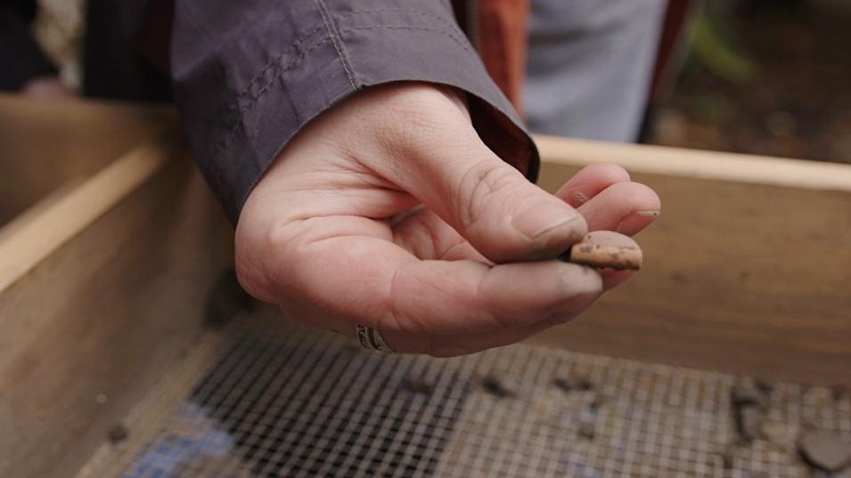 student holding artifact over screen