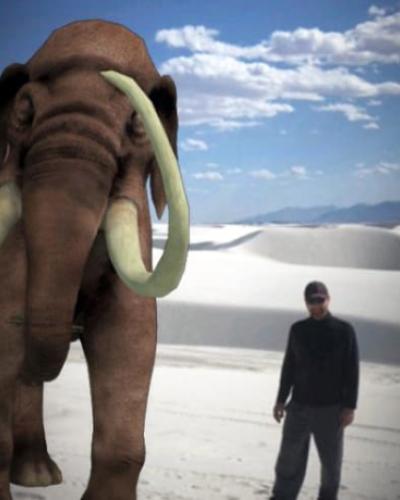Cornell researcher standing in front of large picture of mammoth